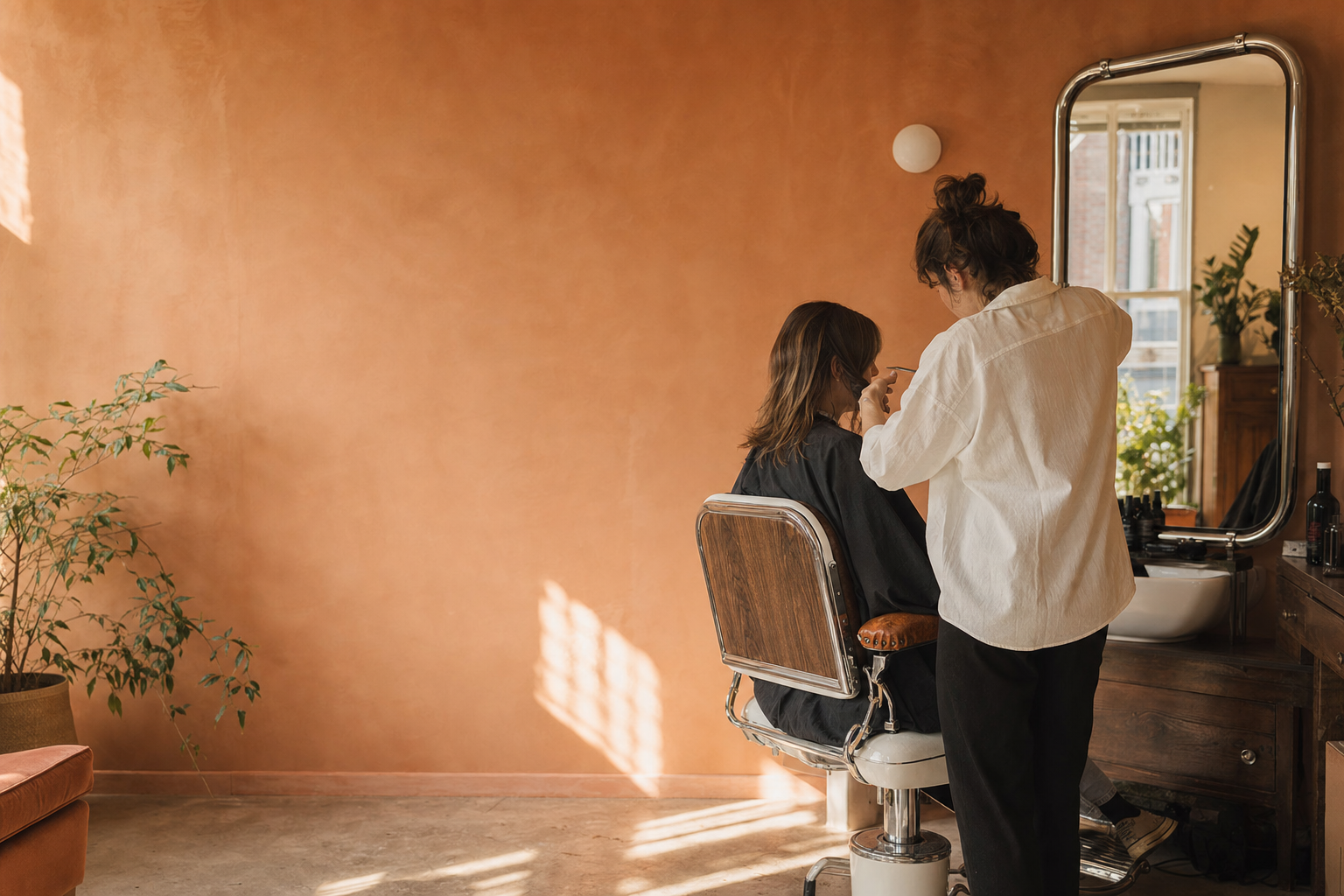 Kapper werkt in een warme terracotta salon